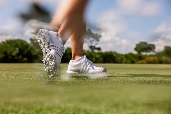 Side view of white adidas golf shoes.
